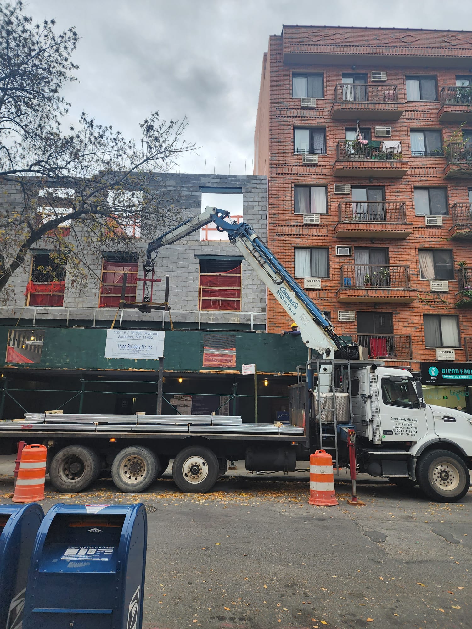 Truck with its boom extended beside a building under construction