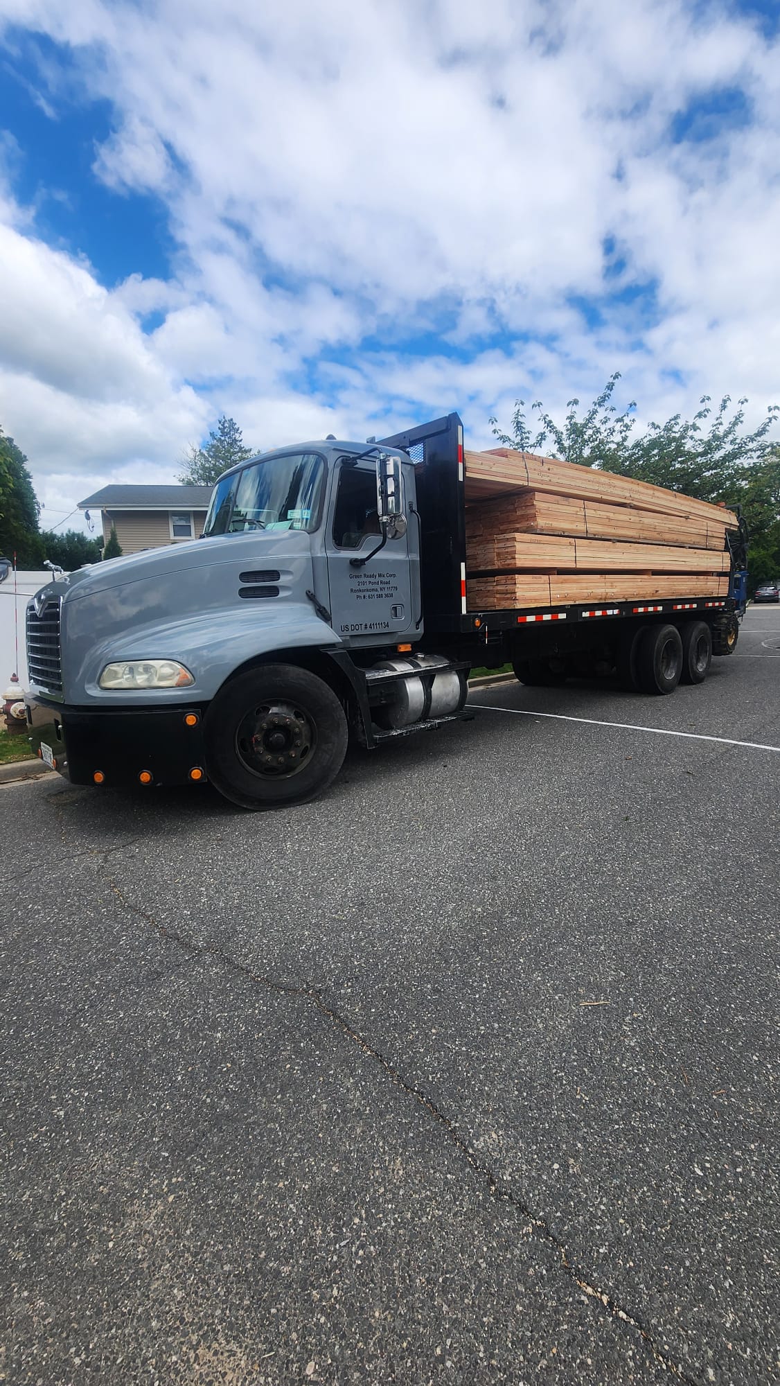 Flatbed truck carrying bundles of framing lumber at a residential jobsite